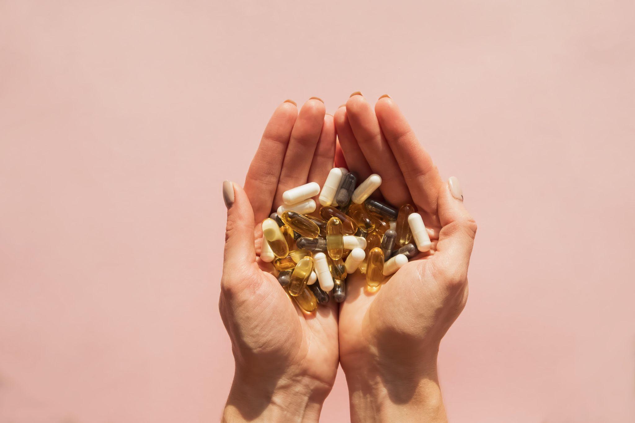 Hands holding a pile of supplement pills