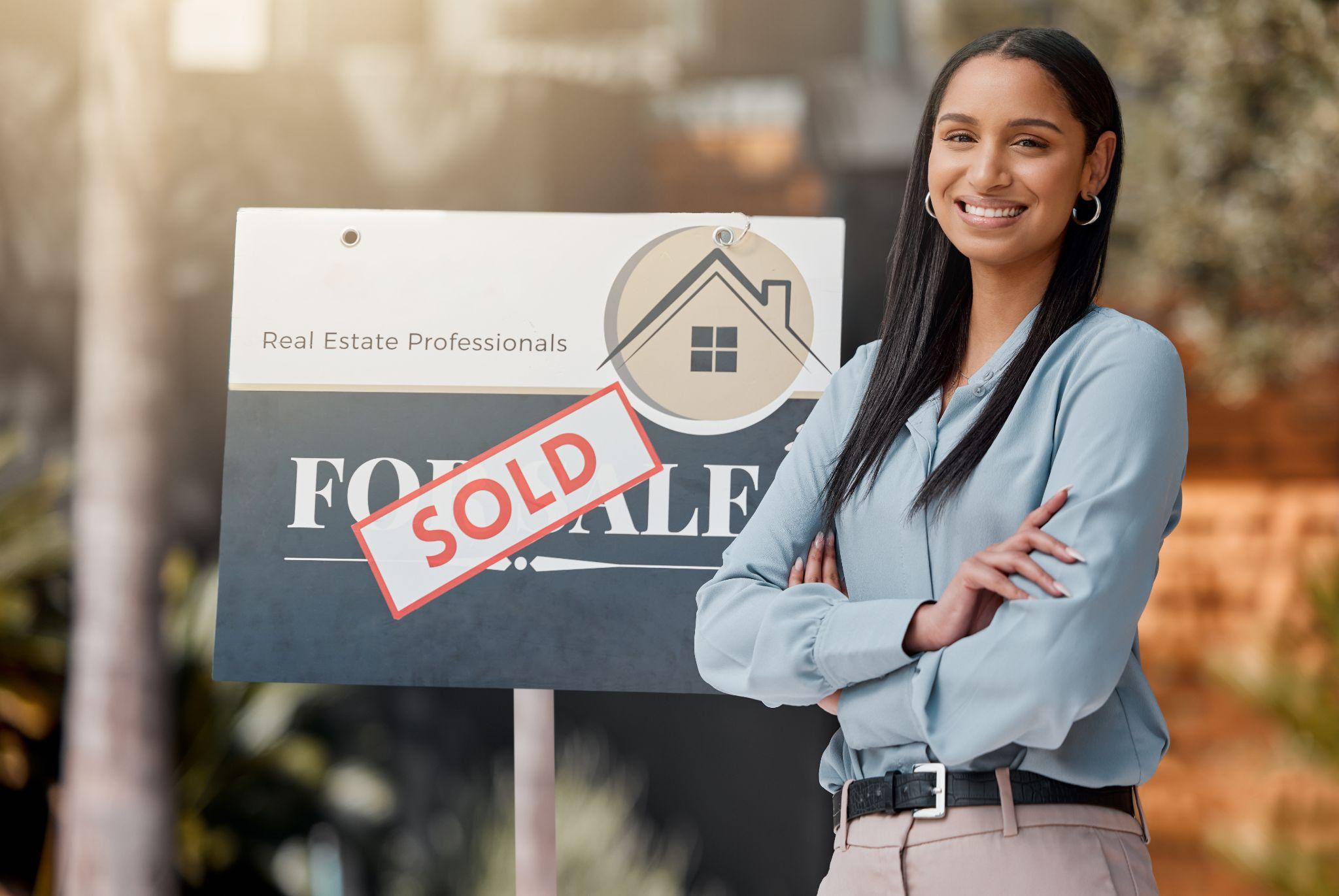 Female real estate agent next to a sold sign